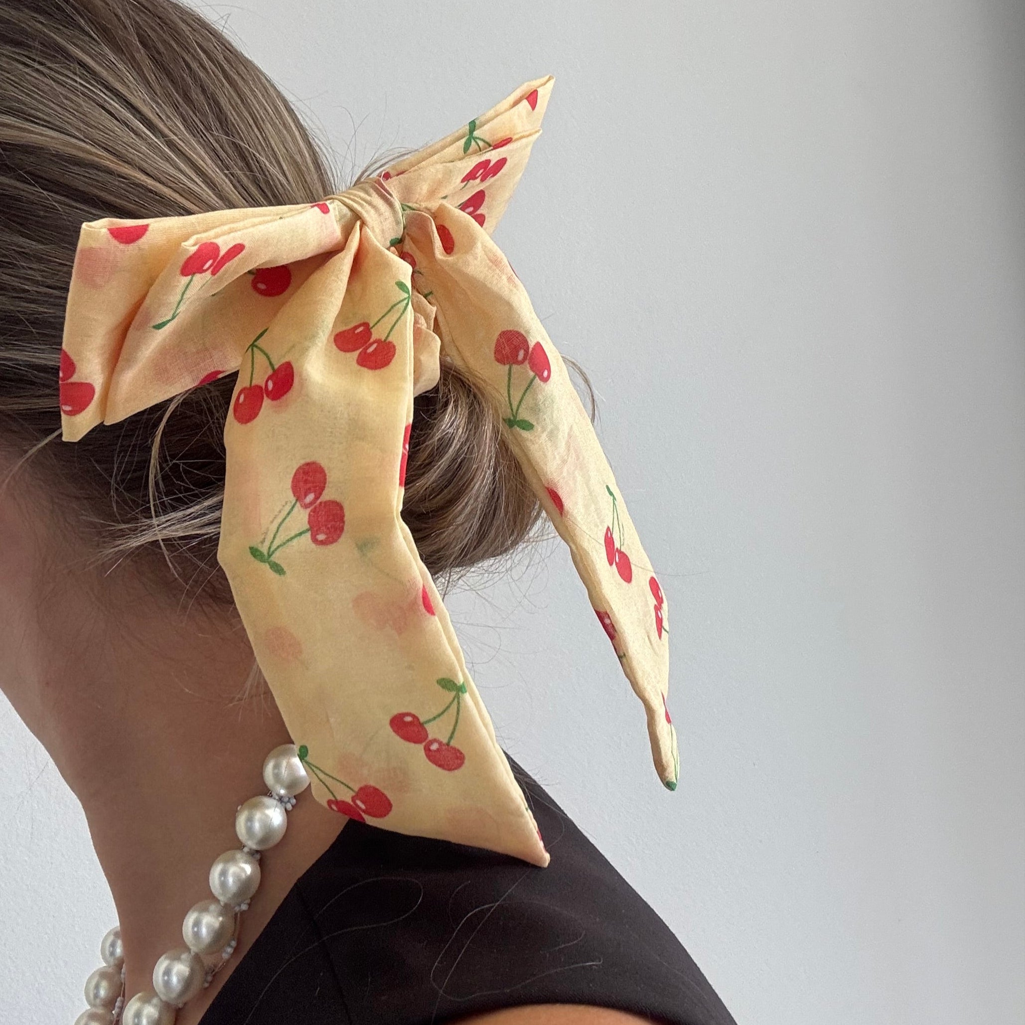 Een scrunchie met een strik en kersen erop