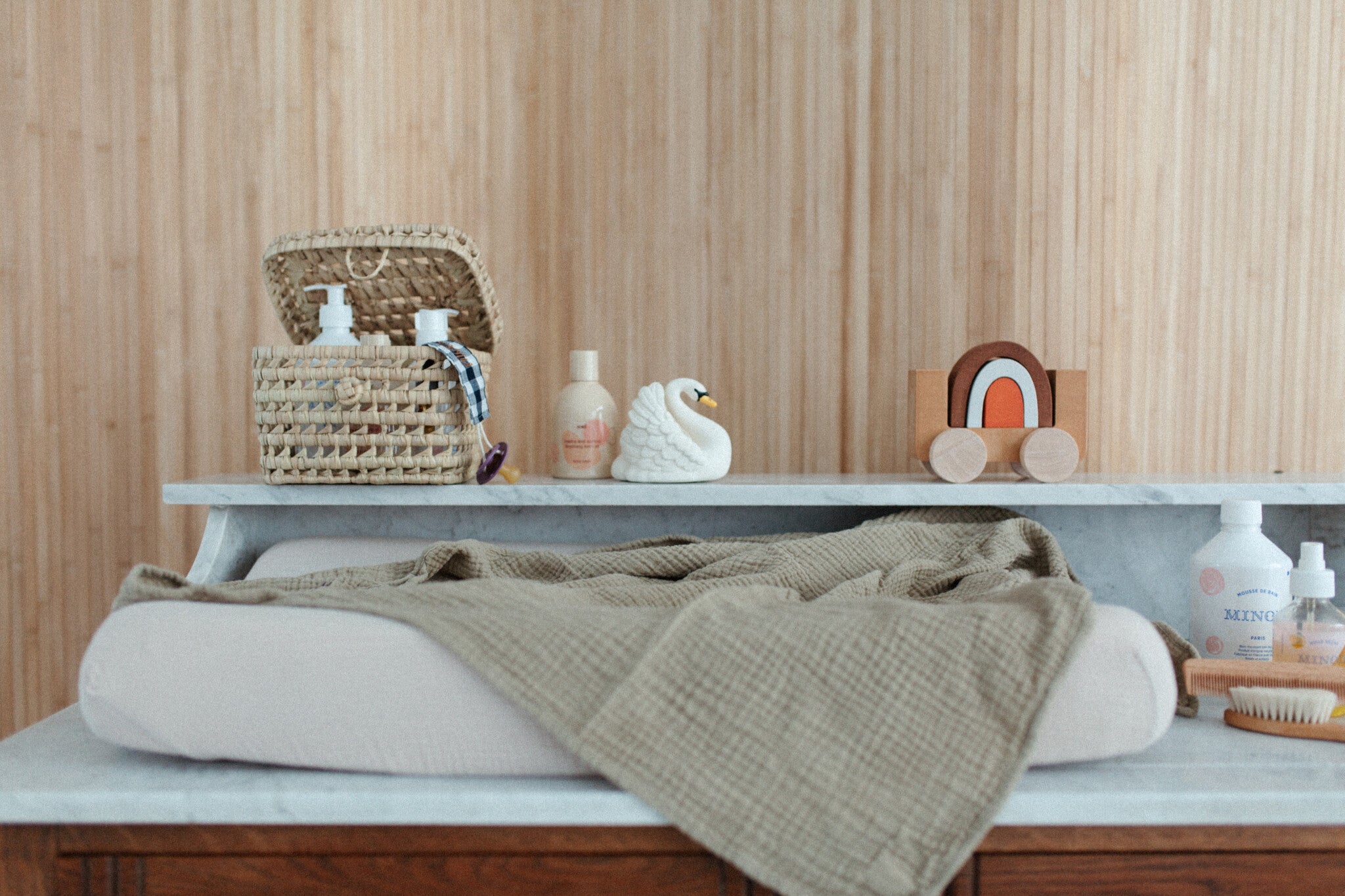 Commode met aankleedkussen, laken, haarproducten, speelgoed, verzorgingsproducten.