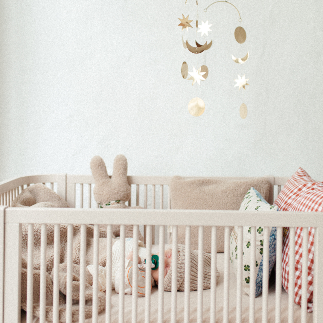 baby ligt in ledikant met knuffel, teddy deken en kussens.