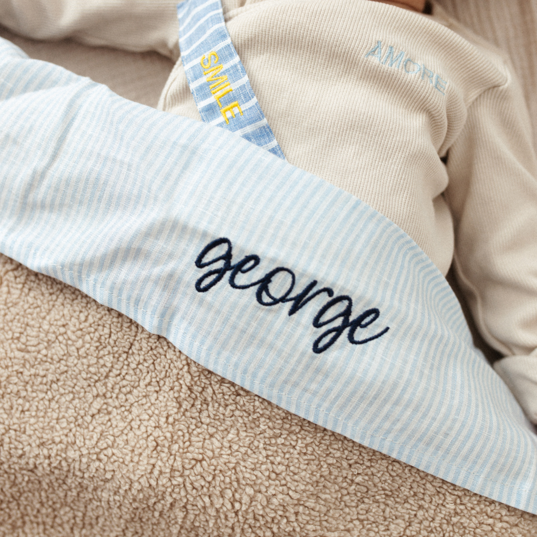 baby ligt onder laken met gepersonaliseerde tekst en speenkoord