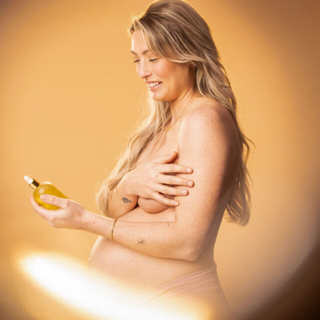 zwangere vrouw met lichaamsolie in haar hand.