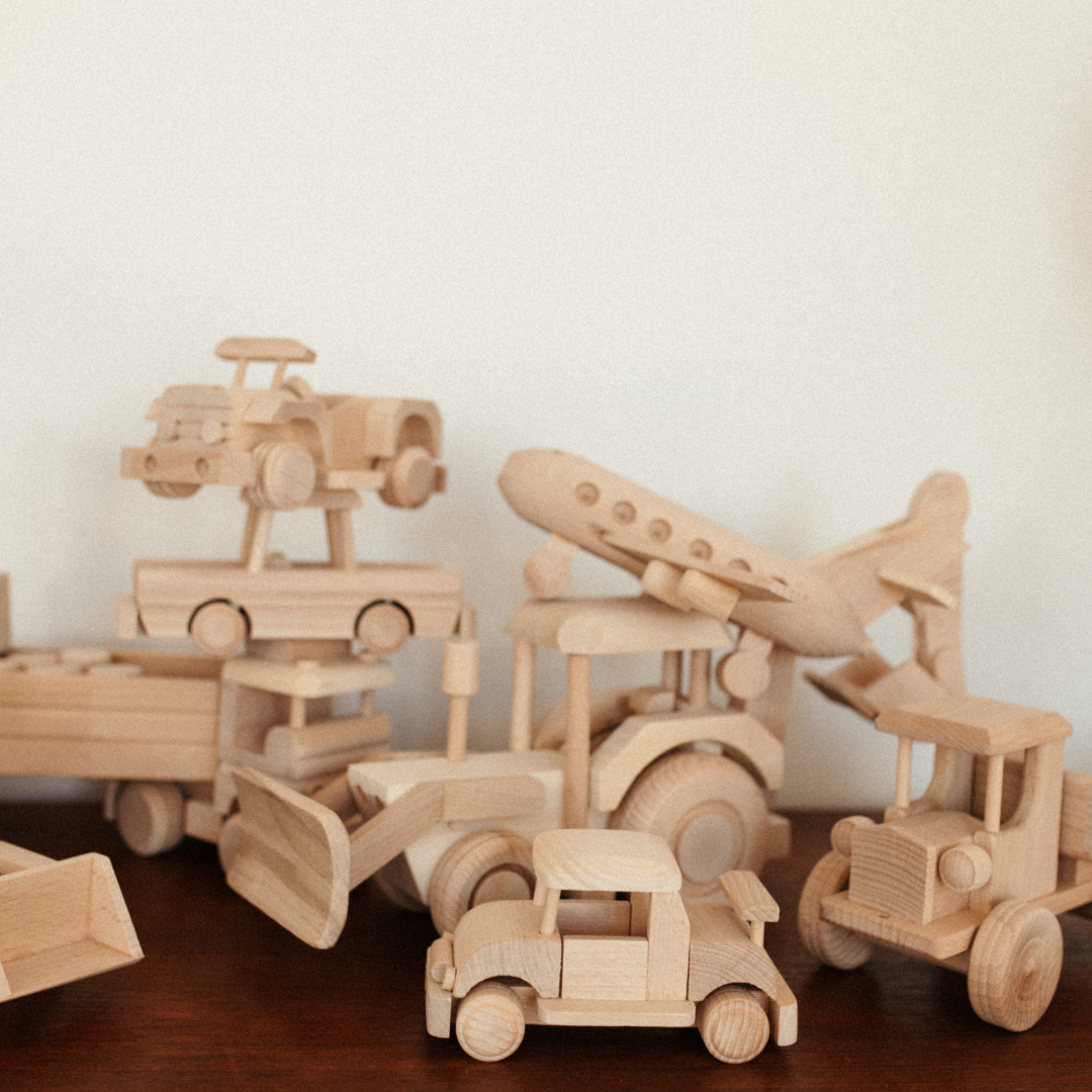 verschillende houten speelgoed van voertuigen op dressoir.