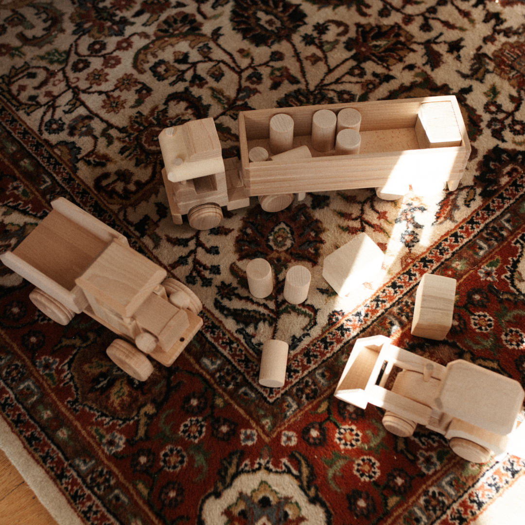 houten speelgoed van voertuigen met blokken op vloerkleden.