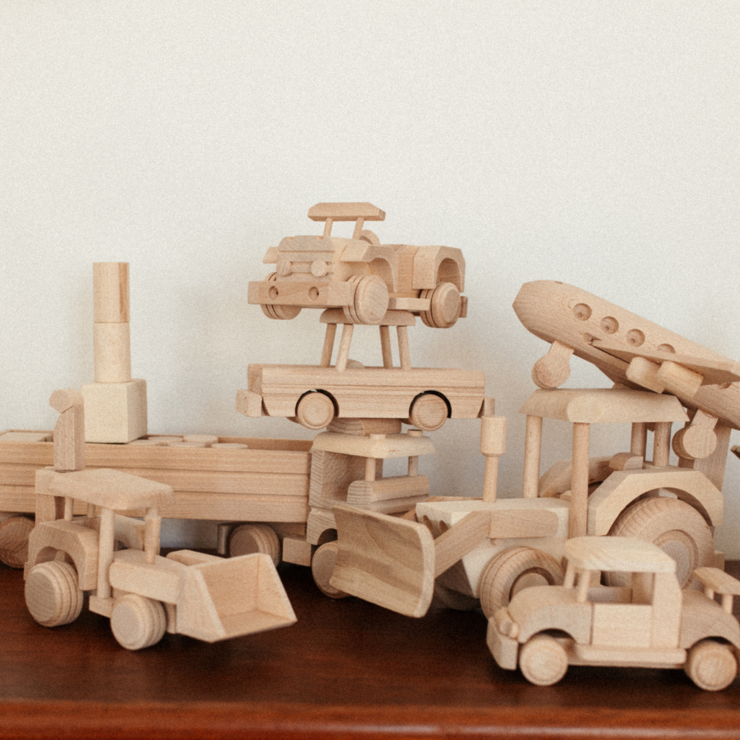 houten speelgoed van verschillende voertuigen op dressoir.