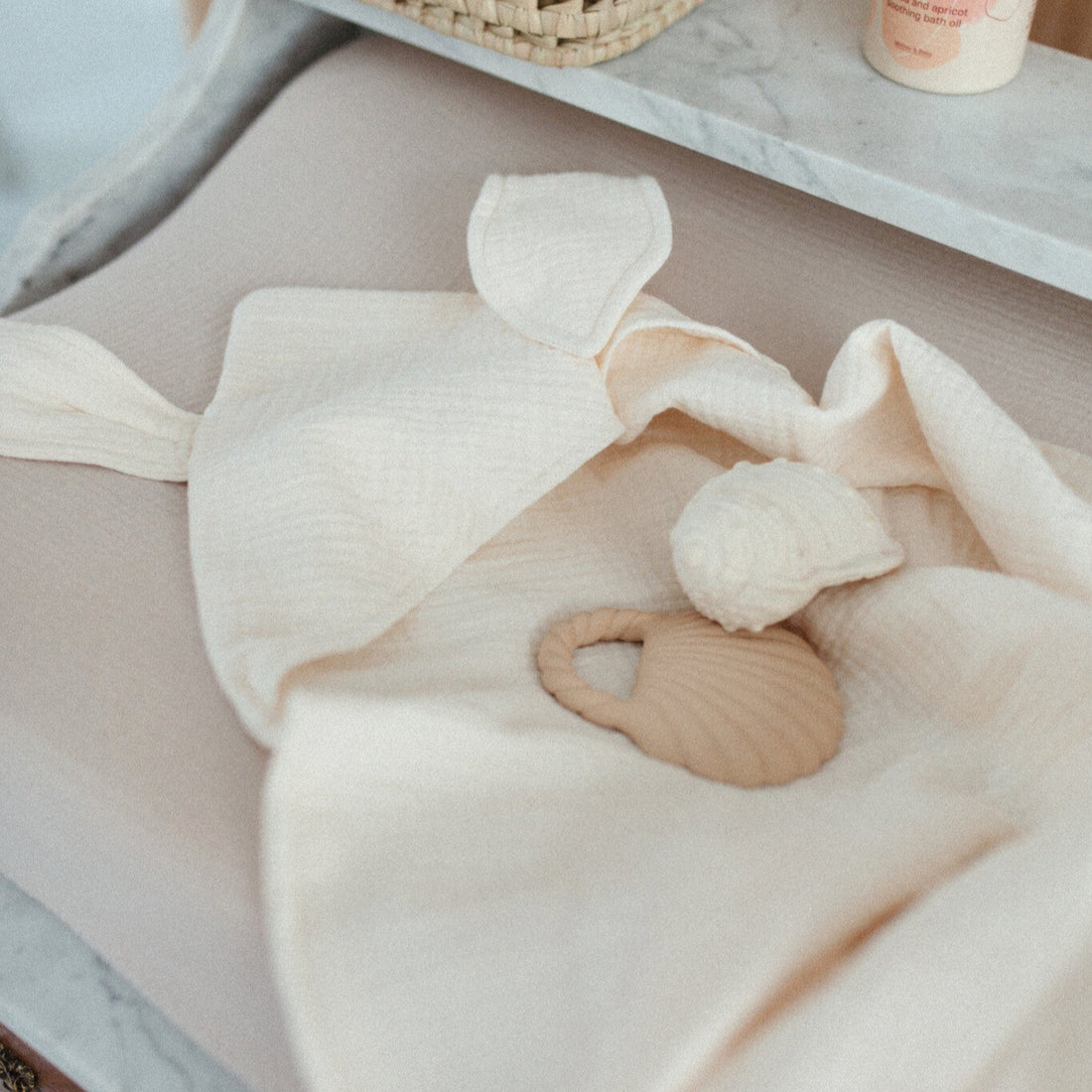 handdoek met capuchon liggend op een commode met verzorgingsproducten en bijtringen