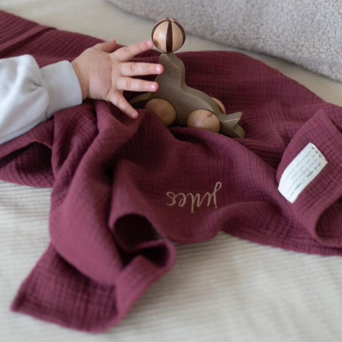 babyhandje pakt houten speelgoed die op een laken met tekst ligt. 