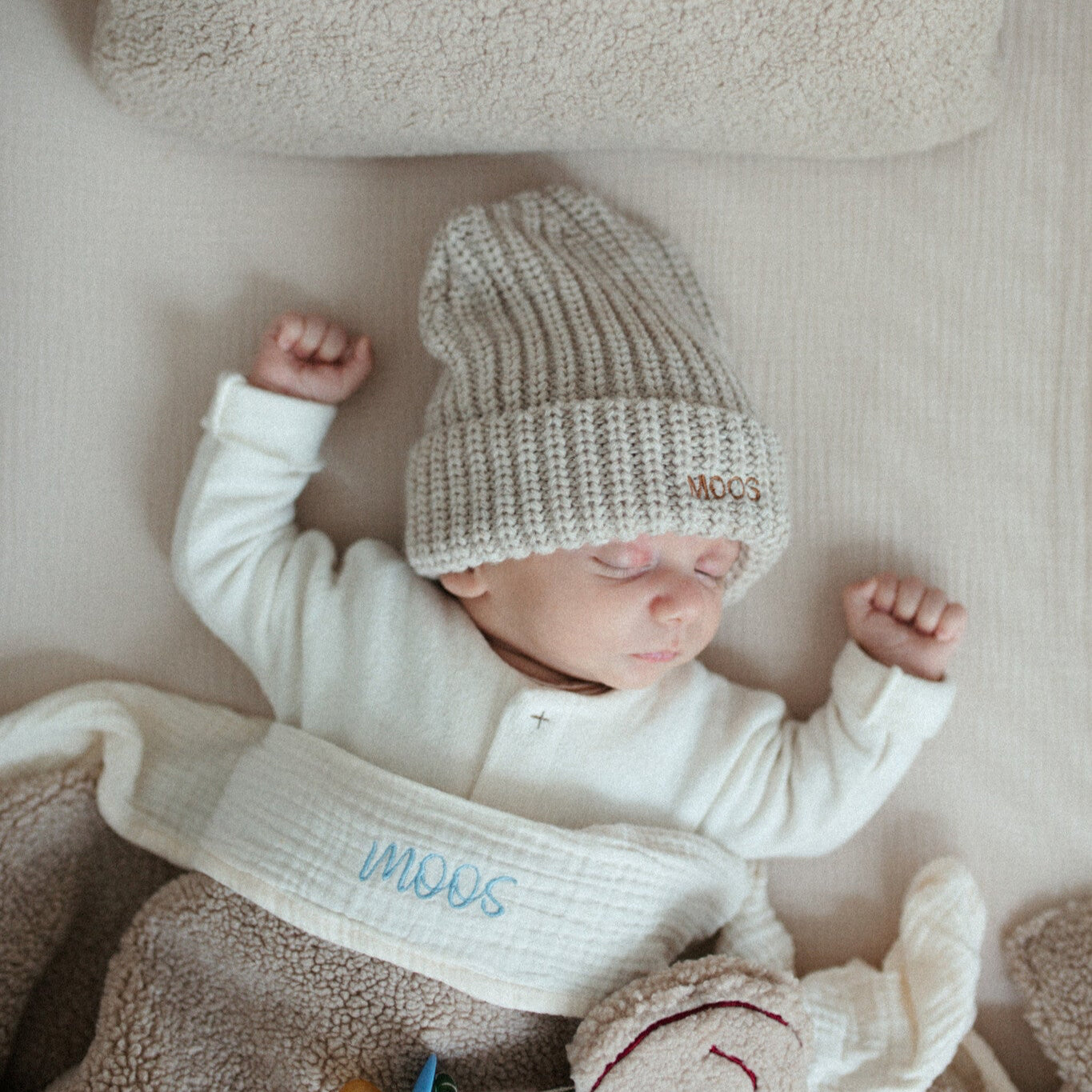 baby ligt naast teddy kussen 