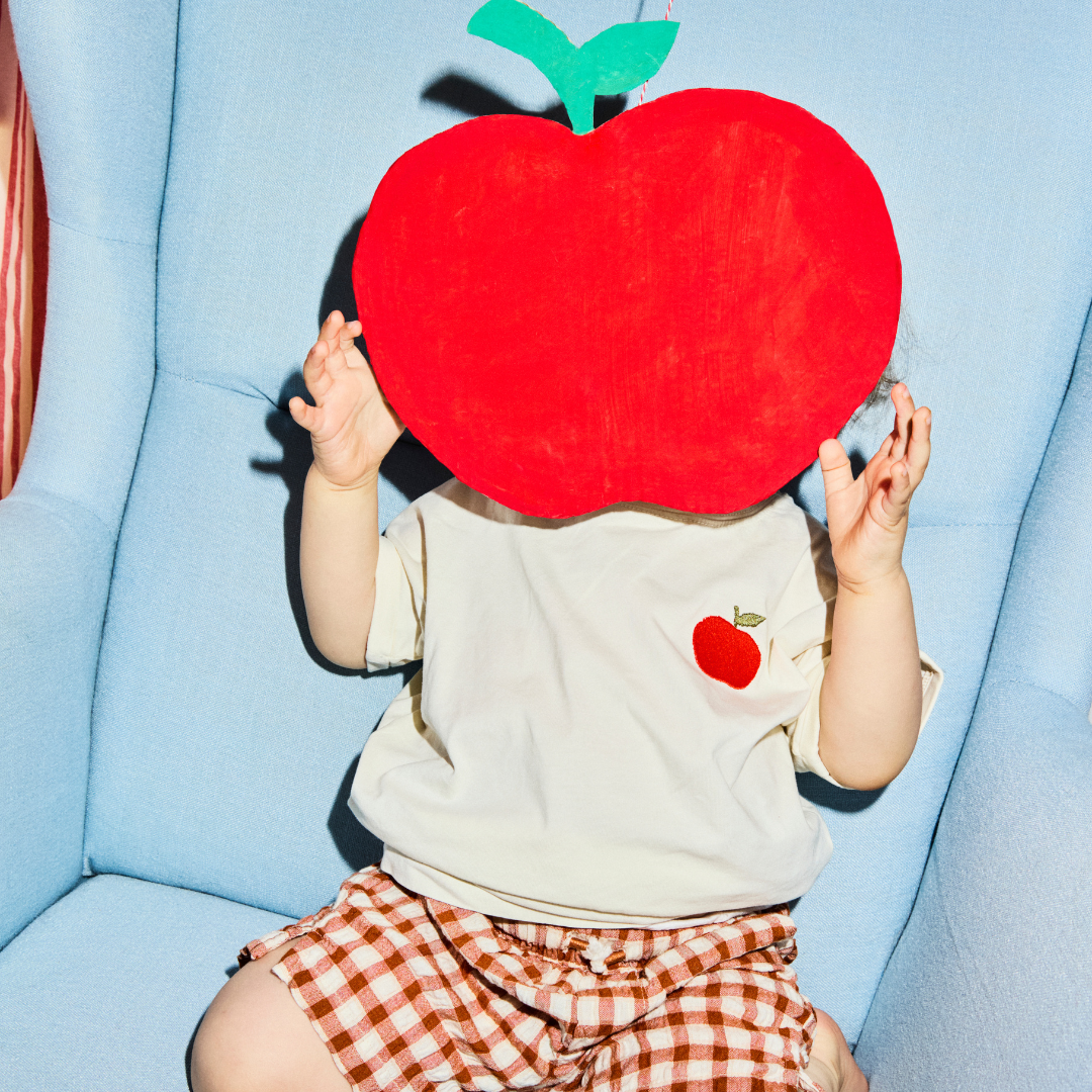 kind heeft witte t-shirt aan met icoon van een appel. 