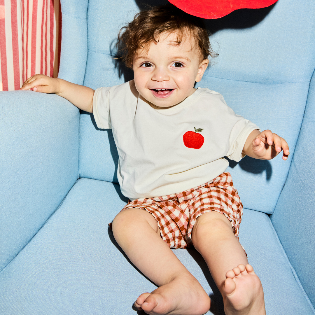 kind zit op stoel en heeft een wit t-shirt aan met icoon. 