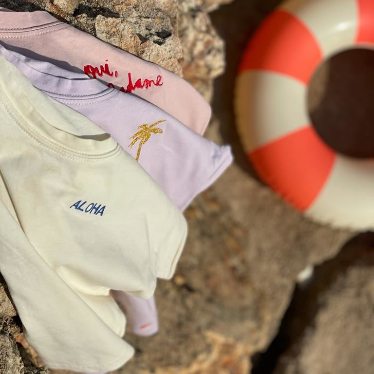 kinder T-shirts met tekst of iconen liggend op een rots. 